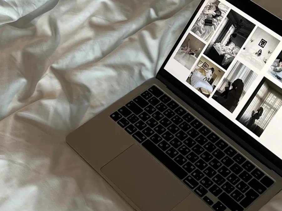 A laptop on a bed showing a contact sheet of finished black-and-white shots