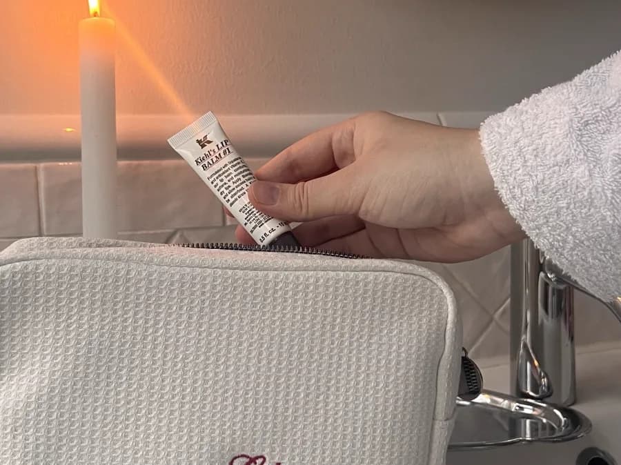 A product held close in hand beside a candle and a cosmetic bag — a UGC shoot