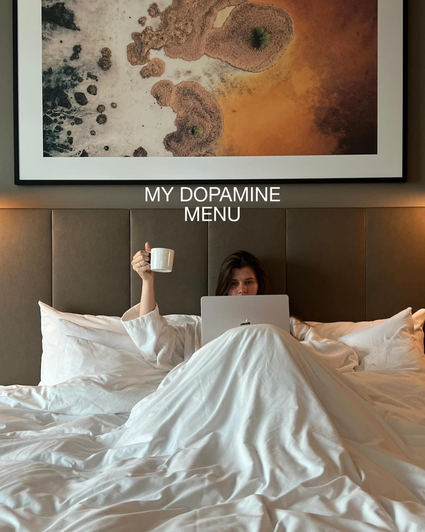 Hotel-room morning: coffee and a laptop in bed under the caption 'My dopamine menu'