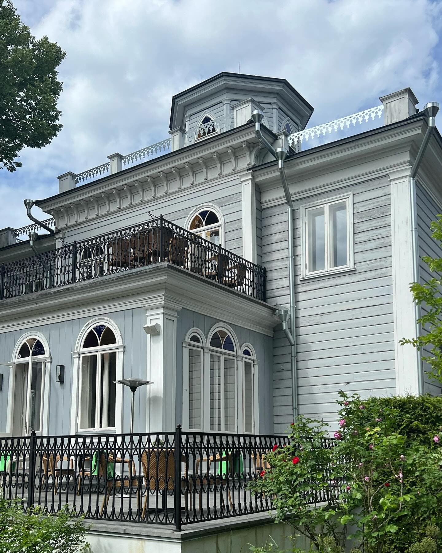 A grey-blue mansion facade with a balcony and wrought-iron railing