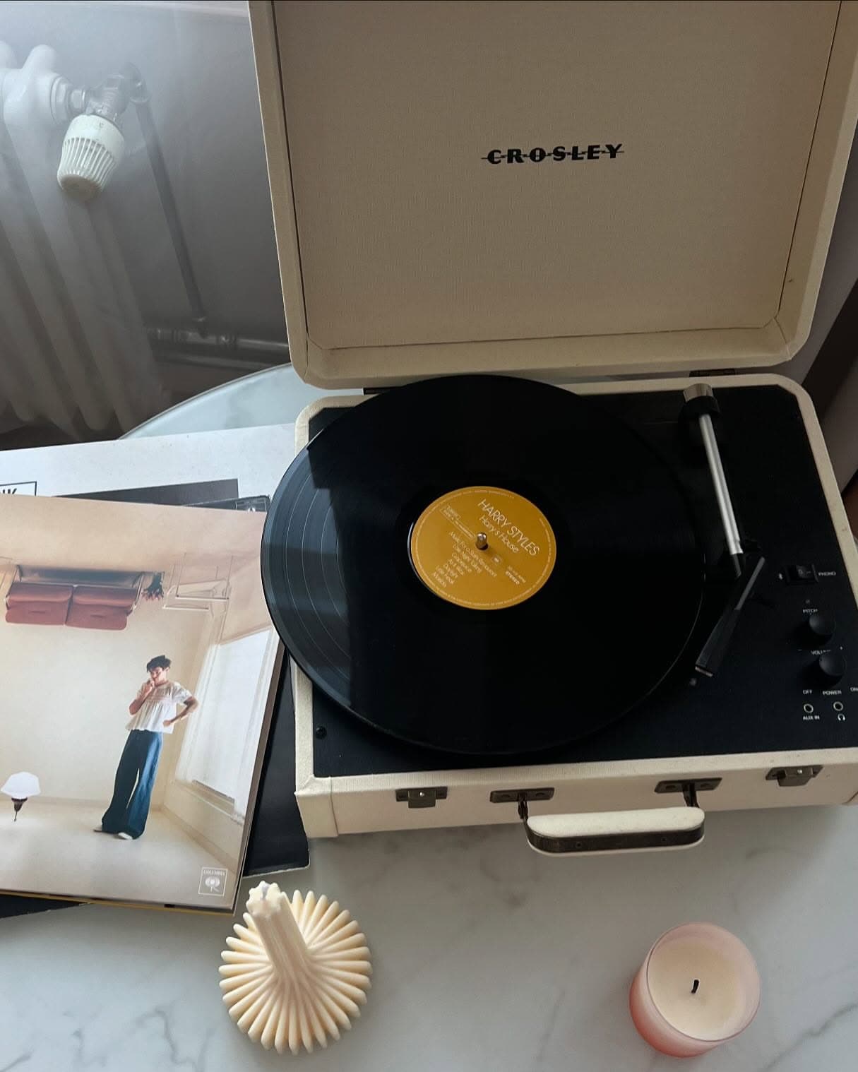 A Crosley record player spinning Harry Styles, candles beside it